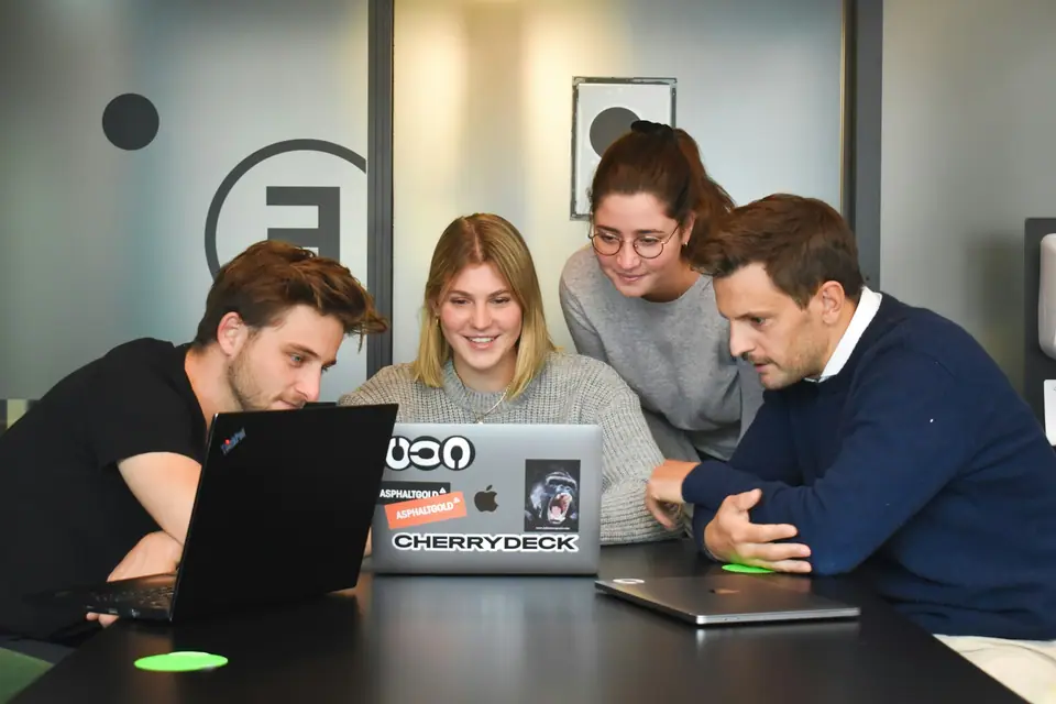 Colleagues laughing together while working on laptops